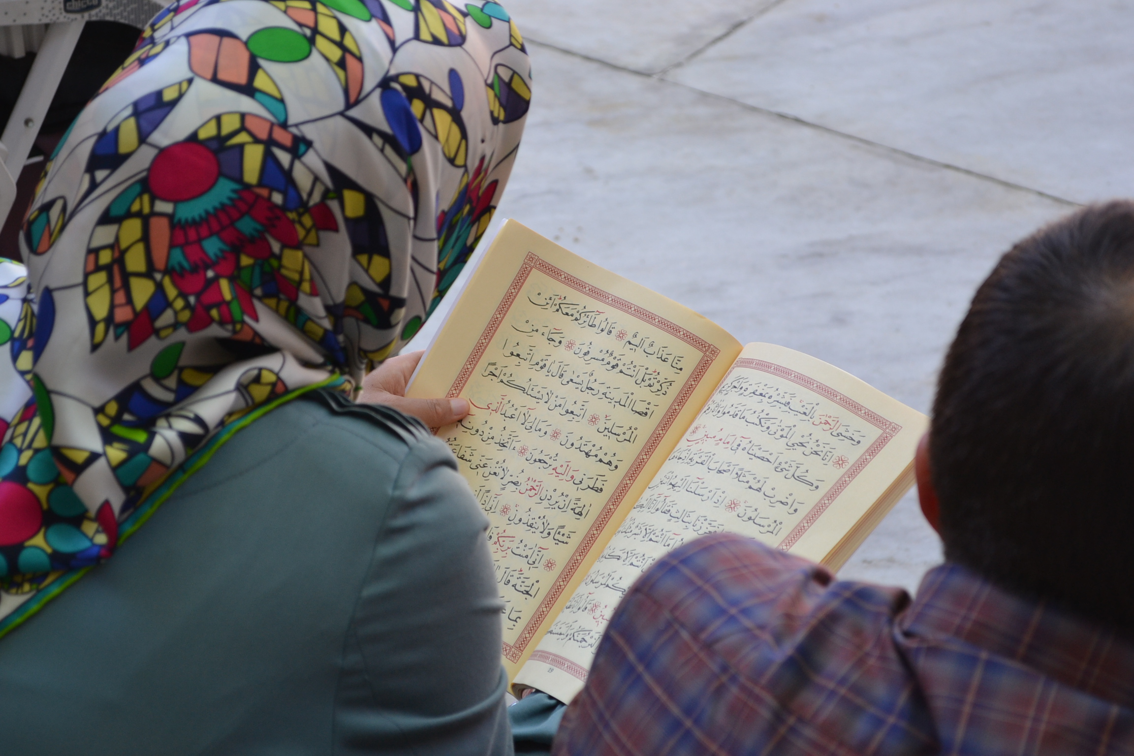 Nainen istuu moskeijan sisäpihalla lukemassa Koraania.