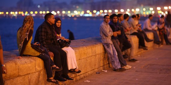Egyptiläisiä nuoria istumassa kävelykadun vieressä.