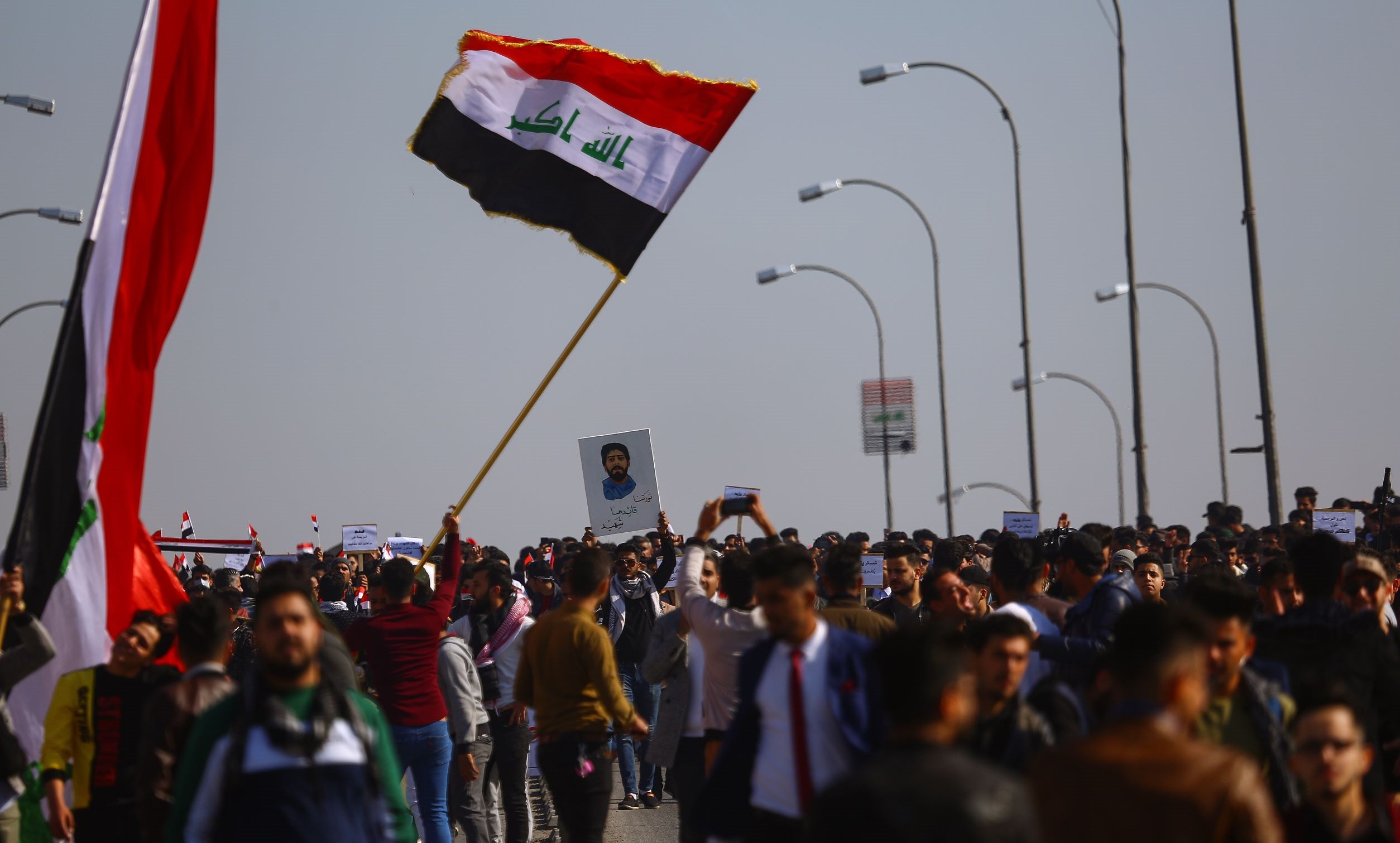 Suuri joukko irakilaisnuoria osoittaa mieltään kadulla. He heiluttavat Irakin lippuja ja pitävät käsissään kylttejä.