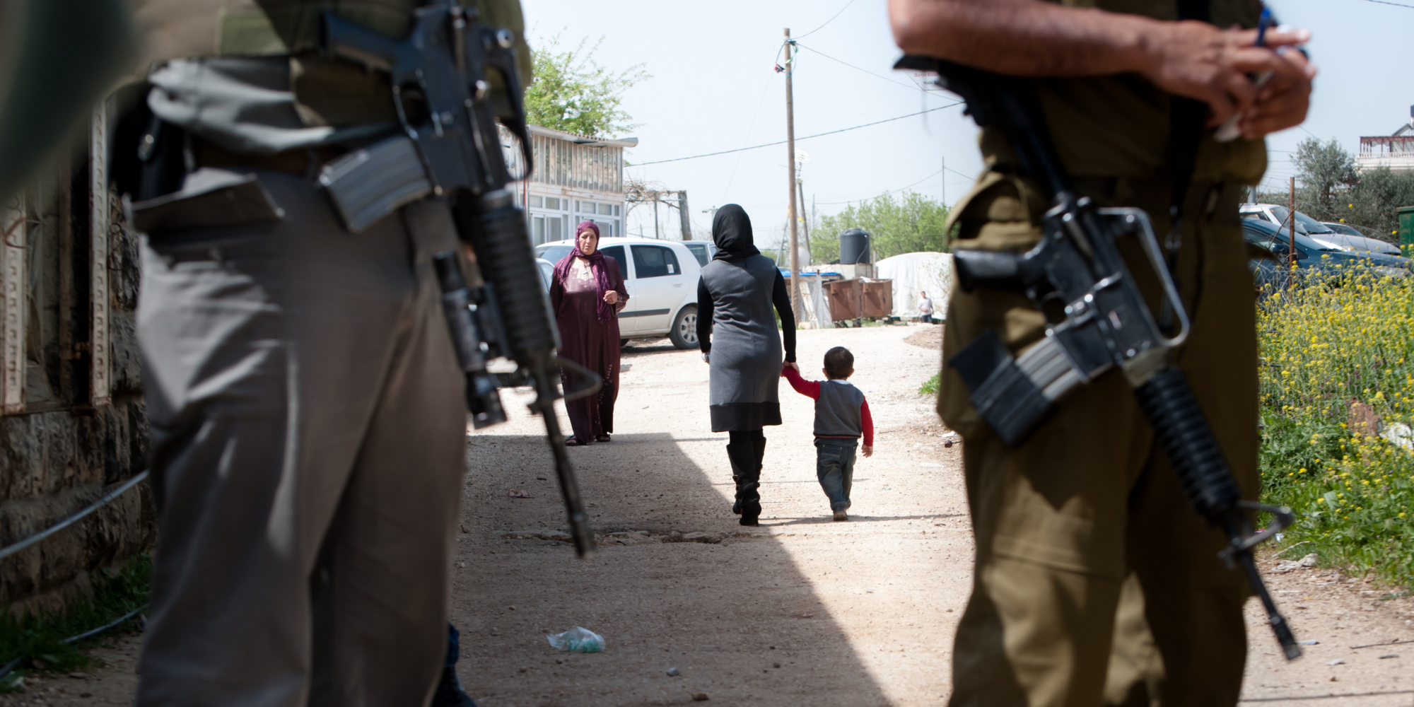 Nainen ja lapsi kävelevät sotilaiden takana.