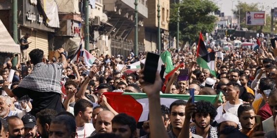 Kuvassa ihmisjoukkoa Kairon kadulla osoittamassa mieltään palestiinalaisten puolesta. Ihmiset kantavat Palestiinan lippuja ja kohottavat nyrkkejään ilmaan.