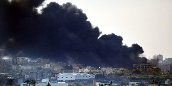 Kuvassa kerrostaloja Gazassa pommituksen jälkeen- Talojen taustalla ilmaan kohoaa paksu, tumma savupilvi.