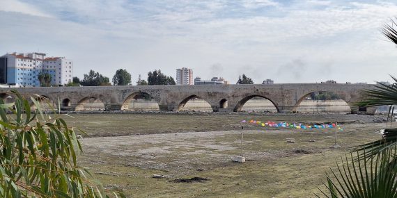 Roomalainen tynnyriholvisilta Sayhan joen yli. Joen uoma on kuiva ja sillan allan on kivikkoa ja nurmikkoa.