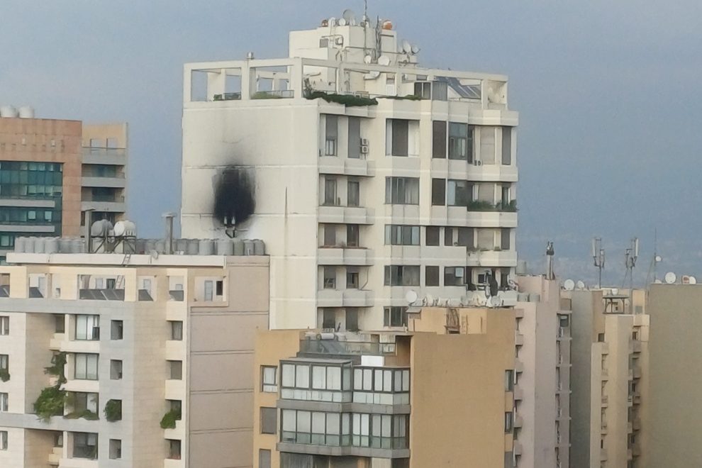 Beirutin kaupunkimaisema, jossa vaalea kerrostalo etualalla; rakennuksen julkisivussa näkyy suuri musta nokijälki usean kerroksen korkeudella. Ympärillä on muita asuinrakennuksia ja taustalla pilvinen taivas.