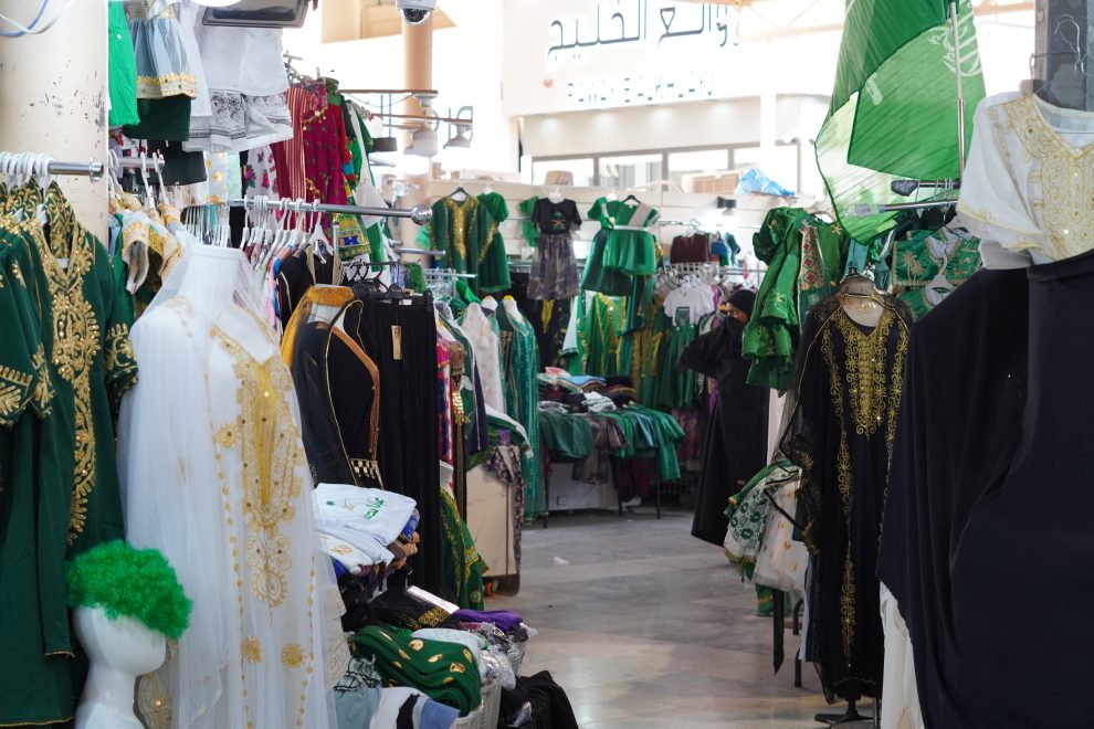 Vihreitä vaatteita täynnä olevien myyntikojujen muodostama käytävä Taiba-market torilla