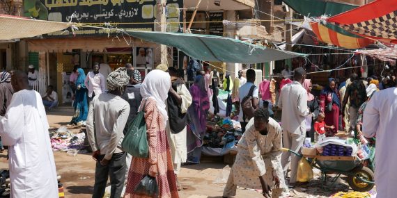 Khartoumin vilkas katumarkkina Sudanissa. Ihmisiä kulkee ja asioi kojuilla, joissa myydään muun muassa vaatteita ja muita tavaroita. Katua reunustavat kauppaliikkeet ja myyntikojut, joita varjostavat värikkäät markiisit.